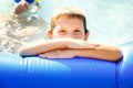 Portrait of a boy in the pool. A happy child swims in an inflatable pool in the garden of letnis on a sunny day Royalty Free Stock Photo