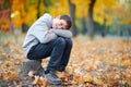 Portrait of boy sitting and dreaming on a stump in autumn city park. Posing on trees with yellow leaves. Bright sunlight and Royalty Free Stock Photo