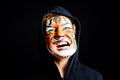 Portrait of a boy with strange and scary gesture, made up with tiger face, isolated on black background