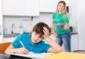 Boy doing homework, mother cooking Royalty Free Stock Photo