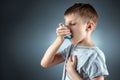 Portrait of a boy using an asthma inhaler to treat inflammatory diseases, shortness of breath. The concept of treatment for cough Royalty Free Stock Photo