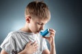 Portrait of a boy using an asthma inhaler to treat inflammatory diseases, shortness of breath. The concept of treatment for cough Royalty Free Stock Photo