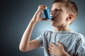 Portrait of a boy using an asthma inhaler to treat inflammatory diseases, shortness of breath. The concept of treatment for cough Royalty Free Stock Photo