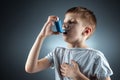 Portrait of a boy using an asthma inhaler to treat inflammatory diseases, shortness of breath. The concept of treatment for cough Royalty Free Stock Photo