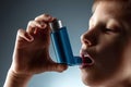 Portrait of a boy using an asthma inhaler to treat inflammatory diseases, shortness of breath. The concept of treatment for cough Royalty Free Stock Photo