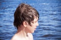 Portrait of boy with wet hair in profile against background of blue water Royalty Free Stock Photo