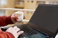 Portrait of boy is working on the laptop with holding tea cup in hand Royalty Free Stock Photo