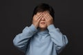 Portrait of boy 10-12 years old covering his eyes with hands. Facial expression concept. Studio shot, white background Royalty Free Stock Photo