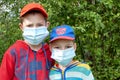 Portrait of boys with medical face mask looking at camera. Sad male child wearing protective mask from virus inside. Concept of