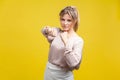 Portrait of brave confident young woman with blonde hair in casual beige blouse, isolated on yellow background