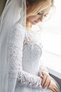 Portrait of a bride in a chic white wedding dress preparing for the wedding ceremony. Portrait of a blonde woman near a window Royalty Free Stock Photo