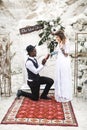 Portrait of bride and groom looking to each other near the wedding arch in boho rustic style. African young man is Royalty Free Stock Photo