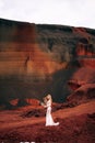 Portrait of a bride model in a golden wedding evening dress, in a yellow-red sandy quarry, in the crater of a volcano in