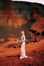 Portrait of a bride model in a golden wedding evening dress, in a yellow-red sandy quarry, in the crater of a volcano in