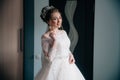 Portrait of a bride posing at home. The girl has already gathered and prepared for her wedding, she corrects her hair Royalty Free Stock Photo