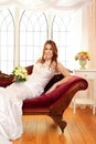 Portrait of bride sitting on fainting couch by window Royalty Free Stock Photo