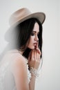 Portrait of bride. A young attractive brunette woman with long black hair in braids. White wedding dress and beige hat Royalty Free Stock Photo