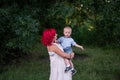 Portrait of bright diversity, extraordinary mother little son embrace in forest. Woman has pink hair