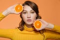 Portrait of a bright positive young woman with oranges in her hands. Orange background
