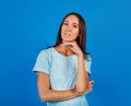 Portrait of a brooding brunette in a blue t-shirt, looking into an empty space, isolated on a blue background