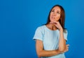 Portrait of a brooding brunette in a blue t-shirt, looking into an empty space, isolated on a blue background