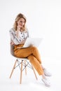 Portrait of brooding girl wearing casual clothes looking at laptop and sitting in chair