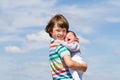 Portrait of a brother hugging his baby sister with cloudy sky
