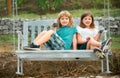 Portrait of brother and sister swinging on swing in summer park outdoors. Little boy and girl kids enjoying summer at Royalty Free Stock Photo