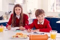 Portrait Of Brother And Sister Wearing School Uniform Doing Homework On Kitchen Counter Royalty Free Stock Photo