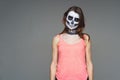 Portrait of brown-haired woman with terrifying halloween skeleton makeup in pink football and a tattoo on his arm over gray backgr
