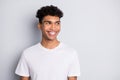 Portrait of brunet optimistic curly guy look empty space wear white t-shirt isolated on grey color background