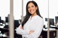 Portrait of a brunette business student in a modern technology office space, standing with arms folded, success concep Royalty Free Stock Photo