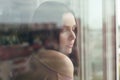 Portrait of Brunette girl standing behind the window with city reflection on the glass Royalty Free Stock Photo