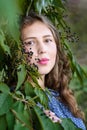Portrait of Brunette girl standing near bird cherry tree with black berries. Girl in blue dress with long hair on the street Royalty Free Stock Photo