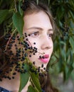 Portrait of Brunette girl standing near bird cherry tree with black berries. Girl in blue dress with long hair on the street Royalty Free Stock Photo