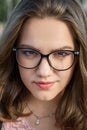 Portrait of brunette girlwith glasses. Girl in black jacket with long hair on the street. Plus size model