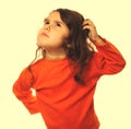portrait brunette kid orange sweater, scratching his head thinki Royalty Free Stock Photo