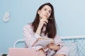 Portrait of brunette lovely creative cheerful girl sitting in bed creating story, making notes in notepad in bedroom Royalty Free Stock Photo