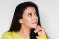 Portrait of brunette pretty dreamy woman looking up with hand on the chin. Young beautiful woman wearing yellow sweater Royalty Free Stock Photo