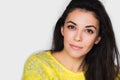 Portrait of brunette pretty woman with beautiful eyes, looking in front. Young happy woman wearing yellow sweater on white wall Royalty Free Stock Photo