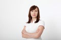 Portrait of brunette serious woman in blank white t-shirt and crossed arms on chest with copy space on white background. Mock up Royalty Free Stock Photo
