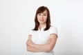 Portrait of brunette serious woman in blank white t-shirt. Crossed arms on chest. Copy space on white background. Mock up and moth Royalty Free Stock Photo