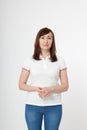 Portrait of brunette serious woman in blank white t-shirt and crossed arms on chest with copy space on white background. Mock up Royalty Free Stock Photo