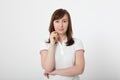 Portrait of brunette serious woman in blank white t-shirt. Crossed arms on chest. Copy space on white background. Mock up Royalty Free Stock Photo