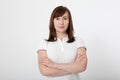 Portrait of brunette serious woman in blank white t-shirt and crossed arms on chest with copy space on white background. Mock up Royalty Free Stock Photo