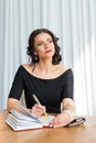 Portrait of a brunette business woman coach sitting at the teacher`s table with a notebook and pen and dreamly looking to the sid Royalty Free Stock Photo