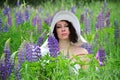 Portrait of a brunette in a white hat in a field of flowering lupins