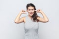 Brunette woman covers ears as hears very loud noise or music, clenches teeth ignores something noisy Royalty Free Stock Photo