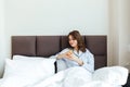 Portrait of a brunette woman drinking orange juice while sitting on bed at home Royalty Free Stock Photo