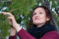 Portrait of brunette woman with long hair and brown eyes standing in pine forest. Cute young woman dressed in brown